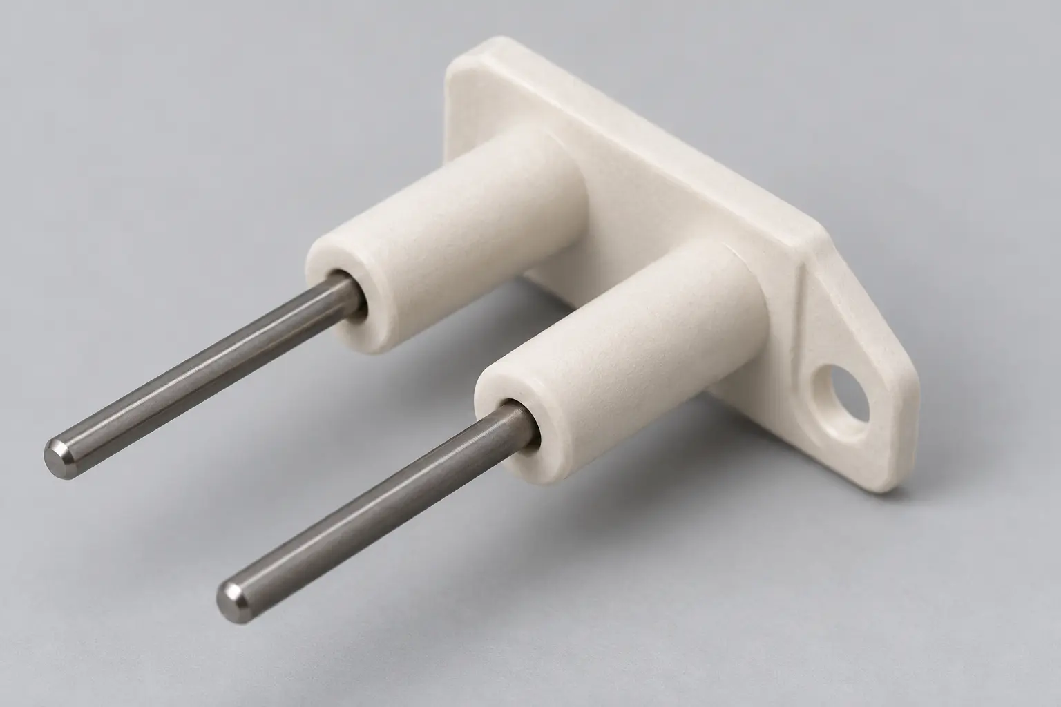 Close-up of the alumina ceramic body and mounting bracket of a twin-pin fireplace spark electrode